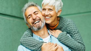 Älterer Mann und ältere Frau umarmen sich.