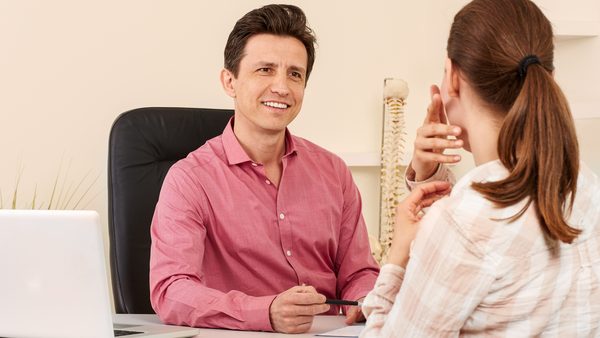 Frau bei der Anamnese in der Hausarztpraxis aufgrund von Bronchitis-Symptomen