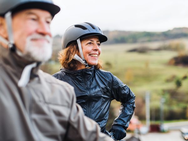Älteres Paar mit Fahrradhelm genießt Bewegung an der frischen Luft – Aktivität trotz rheumatischen Symptomen