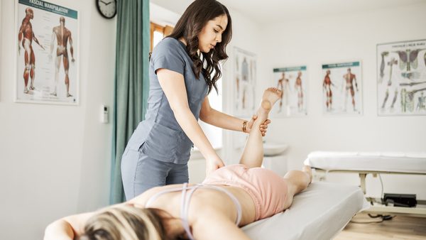 Frau liegt mit dem Bauch auf einer Liege und wird physiotherapeutisch behandelt.