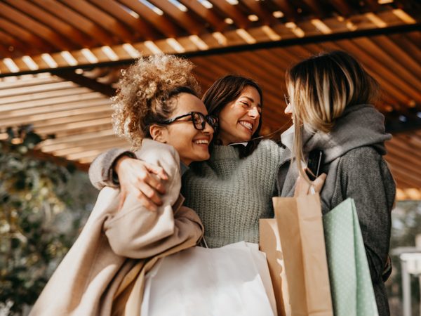 Freundinnen umarmen sich herzlich und lachen gemeinsam.