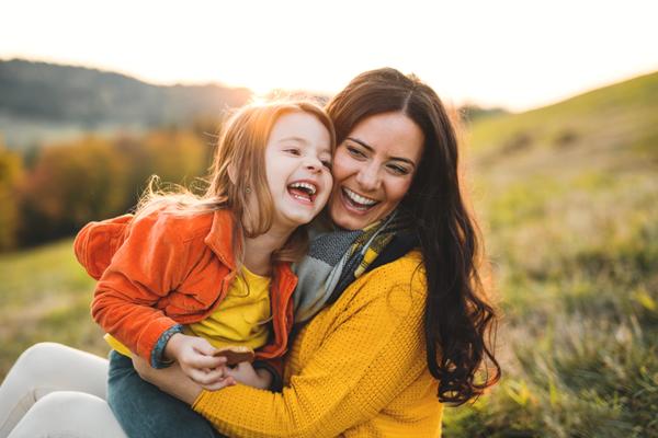 Mutter und Tochter sitzen im Gras und freuen sich