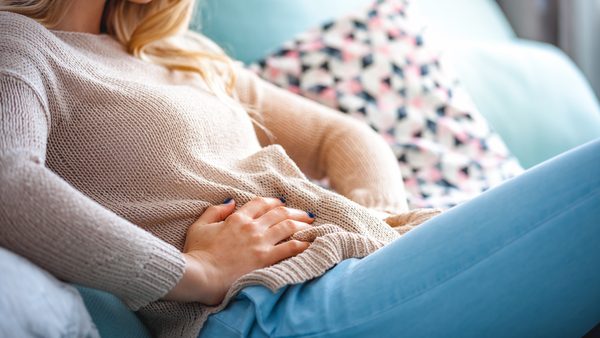 Frau hält sich den Bauch bei Beschwerden im Verdauungssystem.