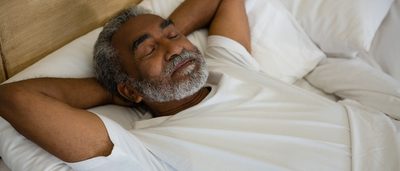 Mann liegt im Bett und schläft erholsam.