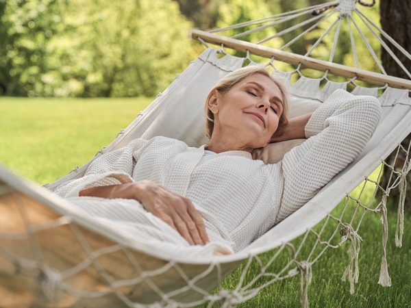 Frau entspannt in Hängematte im Garten.