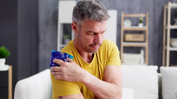 Mann legt sich ein Kühlpad auf die Schulter