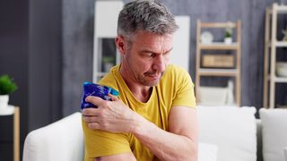 Mann kühlt sich die Schulter mit einem Kühlpad.