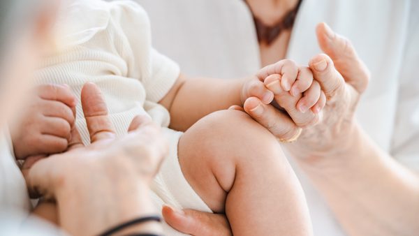 Baby hält sich an den Händen der Eltern fest
