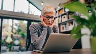 Gestresste Frau sitzt vor Laptop