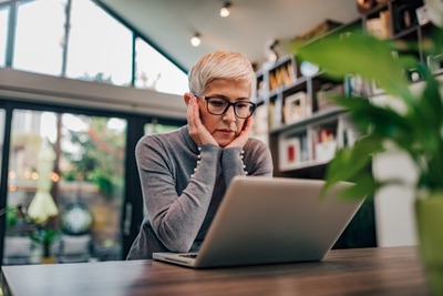 Gestresste Frau sitzt vor Laptop