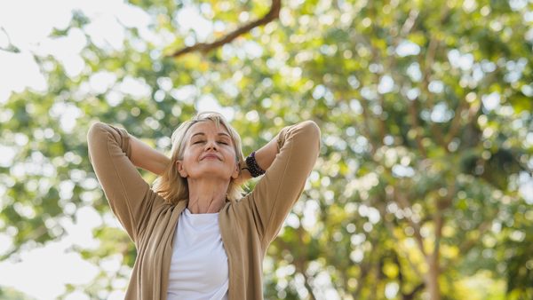 Frau ist in der Natur und atmet bewusst durch