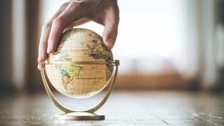 Hand, die kleinen Globus festhält.