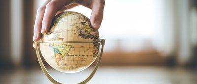 Hand, die kleinen Globus festhält.