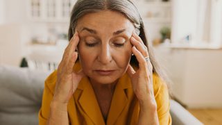 Frau mit gutartigem Lagerungsschwindel hält sich Hände an die Schläfen.