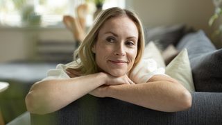 Frau liegt entspannt und lächelnd auf der Coach