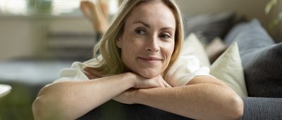 Frau liegt entspannt und lächelnd auf der Coach