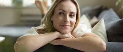 Frau liegt entspannt und lächelnd auf der Coach