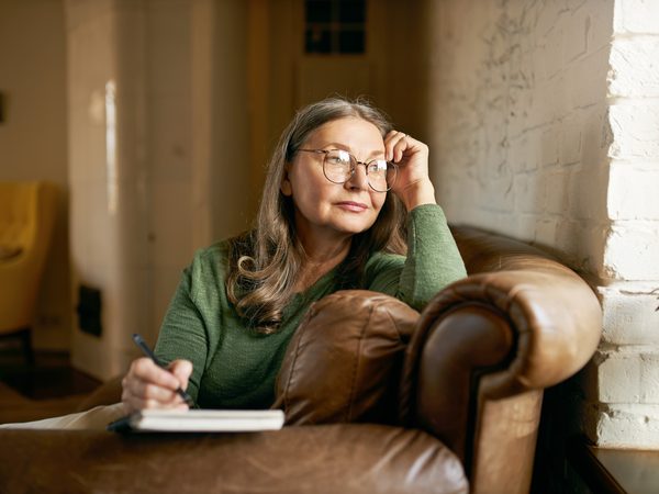 Ältere Frau protokolliert Schwindelsymptome in ein Notizheft.