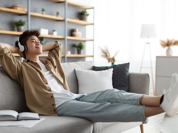 Junger Mann liegt entspannt mit Kopfhörern auf dem Sofa – Symbolbild für Ausgleich und innere Ruhe bei nervösen Beschwerden