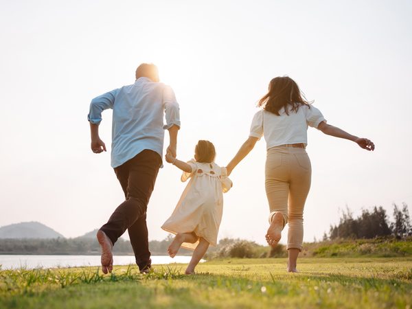 Mutter, Vater und Tochter laufen auf einer Wiese
