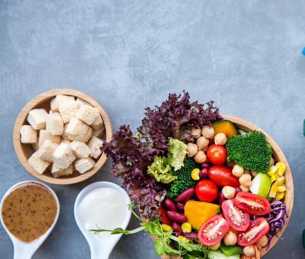 Eine frische Gemüsebowl und Wasserflasche und Sportequipment
