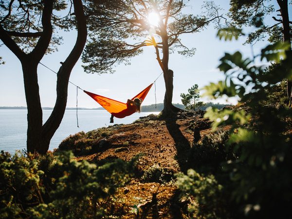 Frau sitzt in einer Hängematte am Wasser