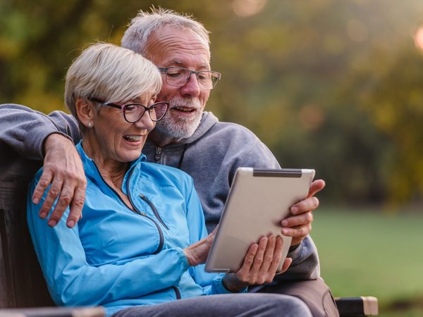 Aktives Seniorenpaar im Park mit Tablet - Symbol für Longevity und selbstbestimmtes Alterwerden