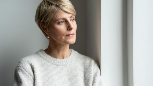 Frau steht am Fenster und denkt nach. 