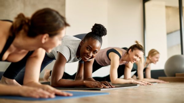 Frauen machen Unterarmstütz in einem Trainingsraum.