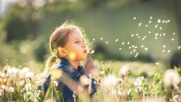 Ein fröhliches Kind genießt die Natur. Ausreichend Schlaf hilft, tagsüber energiegeladen und ausgeglichen zu sein.