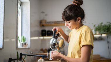 Freu gießt sich Tee in ihre Tasse