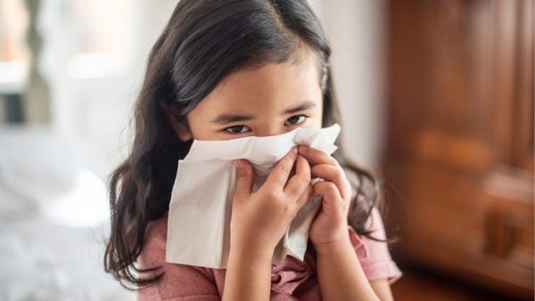 Kleines Mädchen putzt sich die Nase weil es eine Erkältung hat