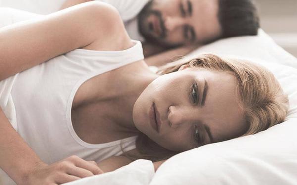 Frau liegt wach und nachdenklich im Bett und kann nicht schlafen