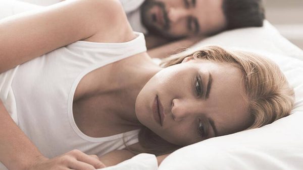 Frau liegt wach und nachdenklich im Bett und kann nicht schlafen