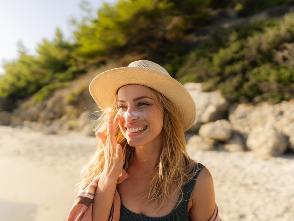 Frau trägt Sonnencreme in der Sonne und schützt ihre Haut.