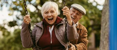 Älterer Mann und ältere Frau beim Schaukeln im Grünen.