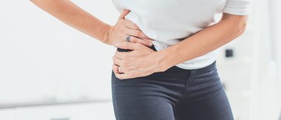 Frau mit Hüftschmerzen hält Hände an Hüfte