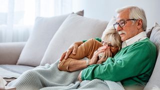 Frau mit Erkältung liegt mit Mann auf der Couch.