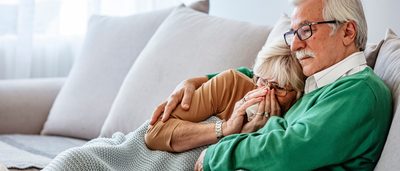 Frau mit Erkältung liegt mit Mann auf der Couch.