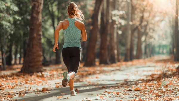Frau joggt durch herbstlichen Park.