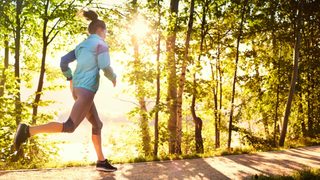 Joggerin läuft bei Sonnenschein im Wald