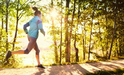 Joggerin läuft bei Sonnenschein im Wald