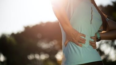 Frau mit Rückenproblemen fasst sich an den Rücken