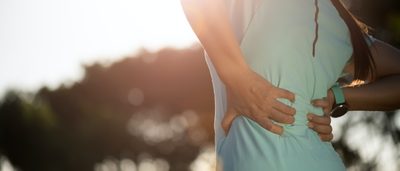 Frau mit Rückenproblemen fasst sich an den Rücken