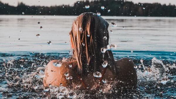 Frau schwimmt draußen in einem See - Bewegung im Alltag.