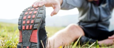 Mann sitzt auf dem Rasen und dehnt seine Wade