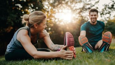 Mann und Frau machen Dehnübungen im Park als Regeneration nach dem Sport.