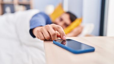 Mann stell Wecker am Handy aus