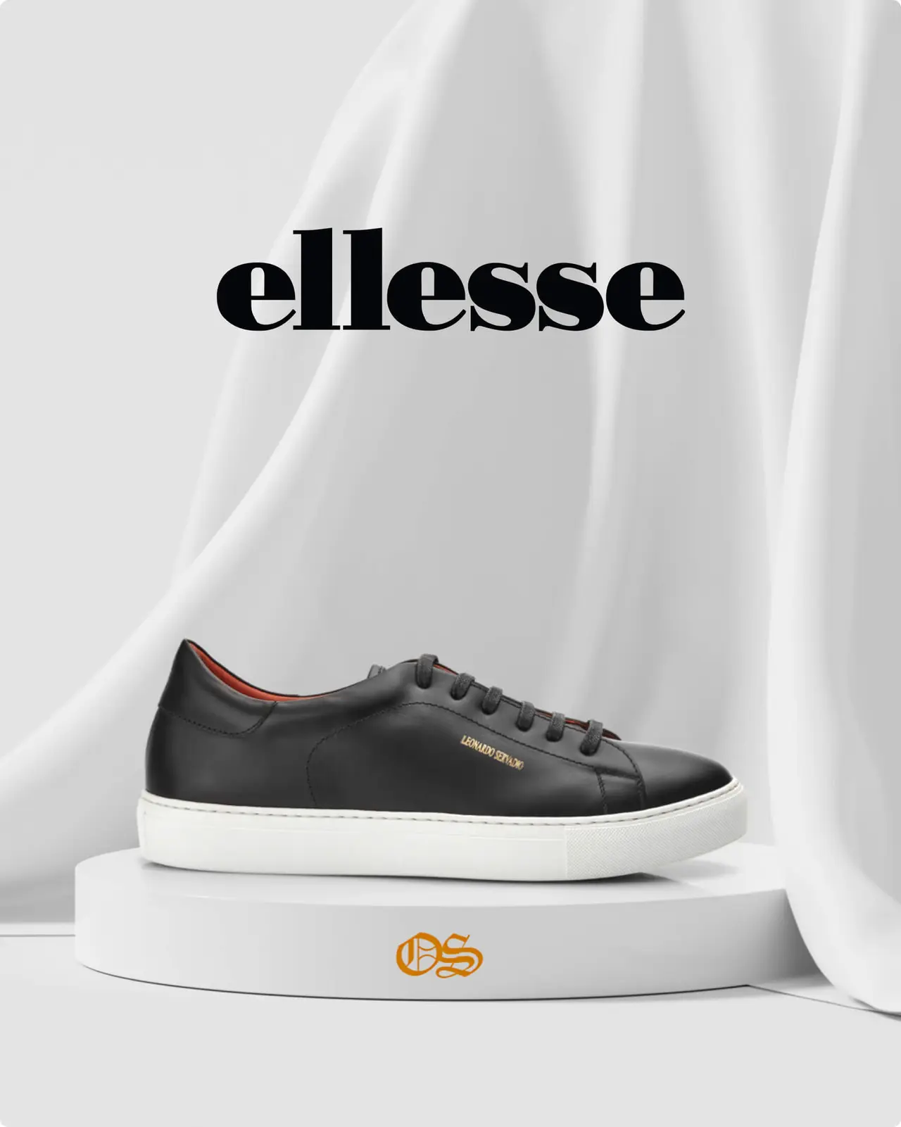 Black leather sneaker with white sole on a round platform, draped white fabric background, "ellesse" logo above the shoe.