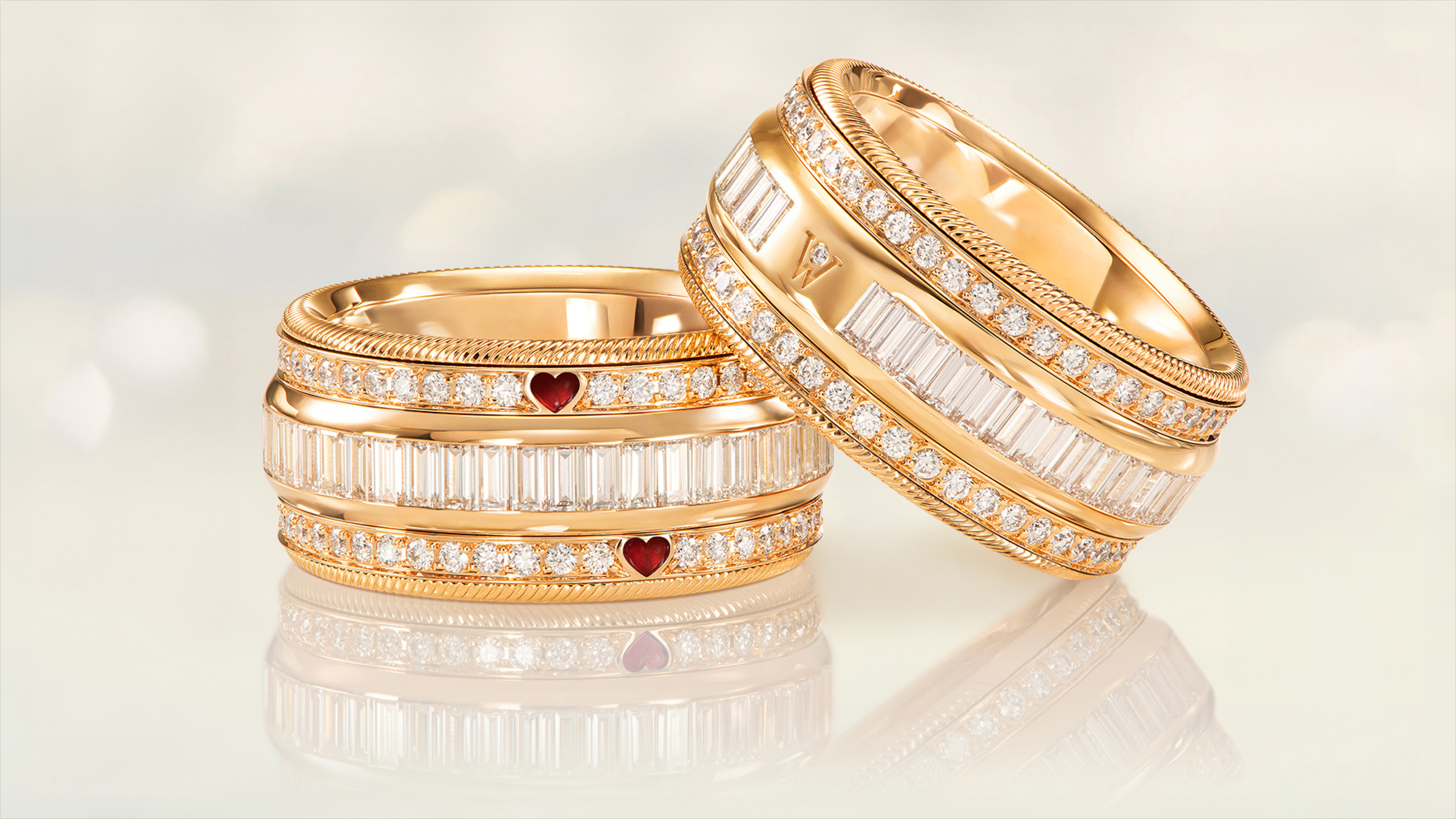 Der drehbare Ring ZWEI HERZEN EINE SEELE vereint edles 18-karätiges Gold mit funkelnden Brillanten und präzise geschliffenen Baguette-Diamanten. Auf grauem Mood Hintergrund.